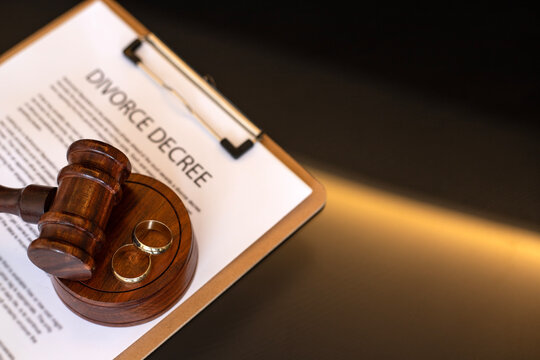 Divorce decree, gavel and wedding rings.