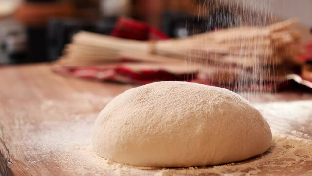 sprinkle flour on the dough. 4k video while preparing the bread sourdough for the first rise. wheat flour sprinkled. bread cooking at home.