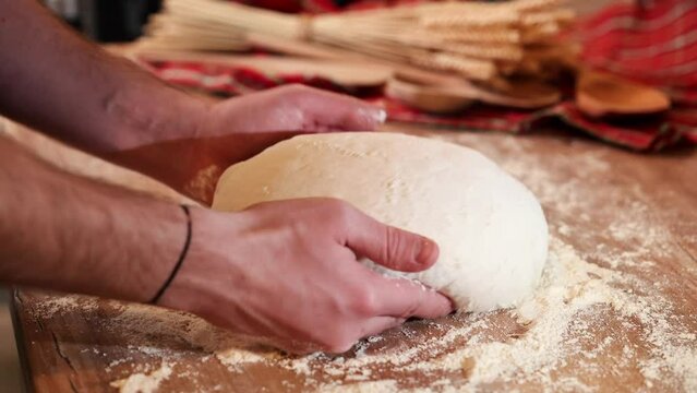 Shaping the sourdough. 4K video with male hands while shaping a home made bread dough after the first rise. Home made fresh bread making process.