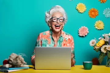 Fotobehang Eine ältere Frau sitzt lachend vor einem Laptop © Herzog