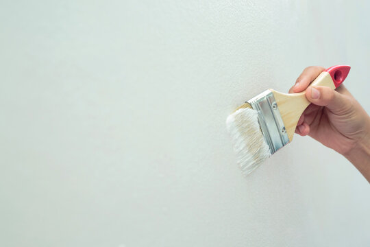 Painter is painting the interior wall white.