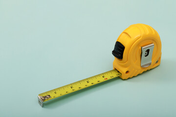 The yellow measuring tape for the mason is placed on a blue background. Soft focus.