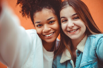 Self-portrait of two happy joyful teen girls of different races making selfie, enjoying friendship