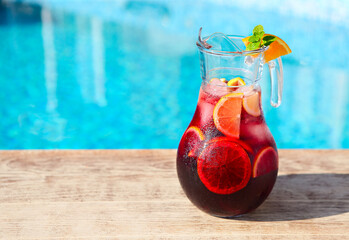 Glass jug of iced sangria with strawberry, orange, apple and lemon