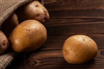 Raw potato food. Fresh potatoes in an old sack on wooden background