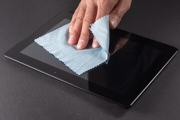 Man's Hand Cleaning Digital Tablet Screen With Soft Blue Cloth