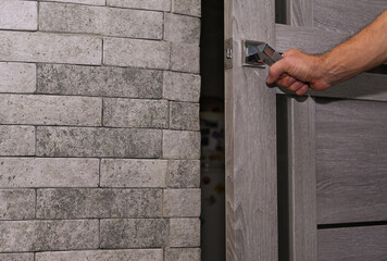 The man's hand opens the door in the room