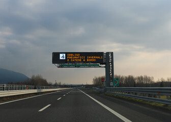 motorway sign indicating that it is mandatory to have snow chains and that there is an automatic...