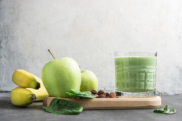 Green detox smoothie in a glass, blended vegetarian drink from spinach leaves, apple, banana fruit...