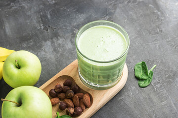 Green detox smoothie in a glass, blended vegetarian drink from spinach leaves, apple, banana fruit...