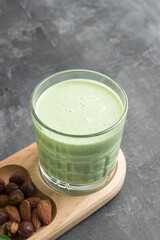 Green detox smoothie in a glass, blended vegetarian drink from spinach leaves, apple, banana fruit...