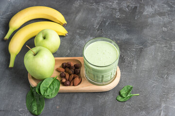Green detox smoothie in a glass, blended vegetarian drink from spinach leaves, apple, banana fruit...
