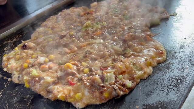 鉄板の上でもんじゃ焼きを焼く