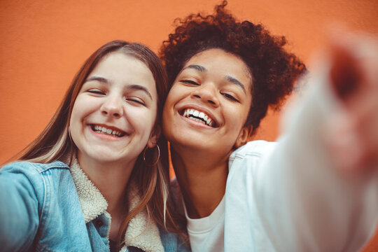 Fototapeta Self-portrait of two happy joyful teen girls of different races making selfie, enjoying friendship.