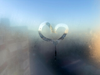 heart shape on steamed window over city view in a rainy day