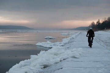 Silhouette of cyclist on wharf on frozen concrete wharf by estuary of  Vistula river, Sobieszewska Island, Poland. 