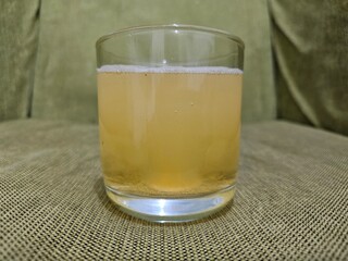A fizzy vitamin C tablet dissolves in a clear cup of water, creating a refreshing, tangy beverage. The effervescent bubbles dance as the vibrant orange hue spreads, embodying health and vitality.