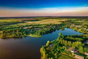 Aerial view of Ostrovno lakes, green fields and trees, small villages, summer at sunset, Belarus, Europe