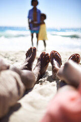 Feet of family on beach, relax and holiday with children, waves and sunshine on tropical island travel together. Black man, woman and kids on ocean vacation in summer with adventure, peace and sky.