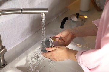 Woman washing moka pot at sink in kitchen, closeup