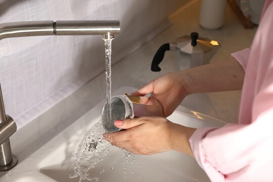 Woman washing moka pot at sink in kitchen, closeup