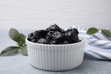 Sweet dried prunes in bowl on grey table, closeup