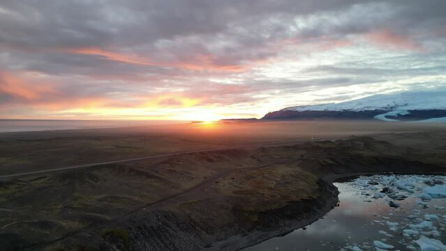 Spectacular drone aerial view at sunset showing Iceland's largest glacier and a car driving from a distance, Jokulsarlon and Vatnaj&ouml;kull gracier, Iceland