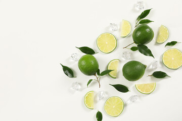 Limes, ice and green leaves on white background, flat lay. Space for text