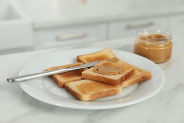 Tasty nut butter and toasts on white marble table, closeup