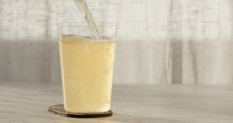 closeup pour ginger beer in a tumbler glass on oak table with copy space