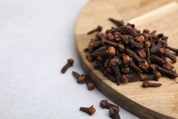 Pile of aromatic cloves on light table, closeup. Space for text