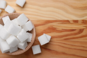 White sugar cubes in bowl on wooden table, top view. Space for text
