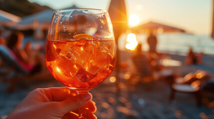 A close-up of an Aperol Spritz in the hand of a beach cafe visitor against the backdrop of the...