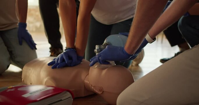 Close-up shooting: Two people perform CPR with the help of a mannequin and an Ambu resuscitation bag. Practical training. Training in first aid