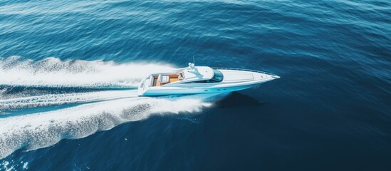 Drone view of a high-speed, white luxury boat sailing on blue water.
