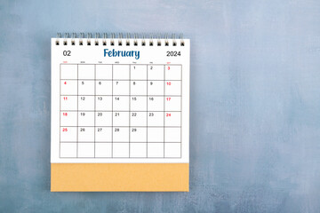 Directly above view of February 2024 desk calendar on blue wooden background.