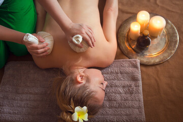 Obraz na płótnie Canvas Woman getting thai herbal compress massage in spa