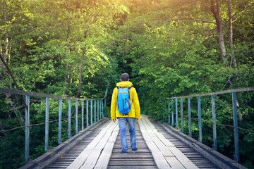 Tourist man walking across wooden bridge