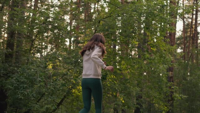 Young lady sprints in forest in evening