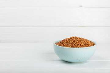 Raw buckwheat in a bowl on a textured background.Wheat grains, porridge, cereals, raw buckwheat in a plate. Healthy food. Porridge. Diet. Organic cerea. Space for text.Copy space.