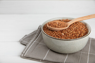 Raw buckwheat in a bowl on a textured background.Wheat grains, porridge, cereals, raw buckwheat in a plate. Healthy food. Porridge. Diet. Organic cerea. Space for text.Copy space.