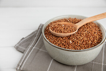 Raw buckwheat in a bowl on a textured background.Wheat grains, porridge, cereals, raw buckwheat in a plate. Healthy food. Porridge. Diet. Organic cerea. Space for text.Copy space.