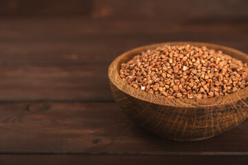 Raw buckwheat in a bowl on a textured background.Wheat grains, porridge, cereals, raw buckwheat in a plate. Healthy food. Porridge. Diet. Organic cerea. Space for text.Copy space.