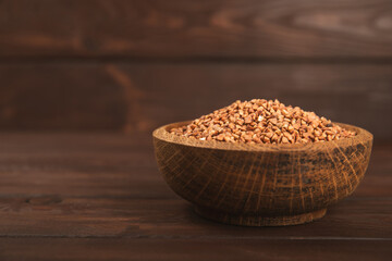 Raw buckwheat in a bowl on a textured background.Wheat grains, porridge, cereals, raw buckwheat in a plate. Healthy food. Porridge. Diet. Organic cerea. Space for text.Copy space.