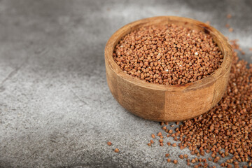 Raw buckwheat in a bowl on a textured background.Wheat grains, porridge, cereals, raw buckwheat in a plate. Healthy food. Porridge. Diet. Organic cerea. Space for text.Copy space.