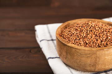 Raw buckwheat in a bowl on a textured background.Wheat grains, porridge, cereals, raw buckwheat in a plate. Healthy food. Porridge. Diet. Organic cerea. Space for text.Copy space.