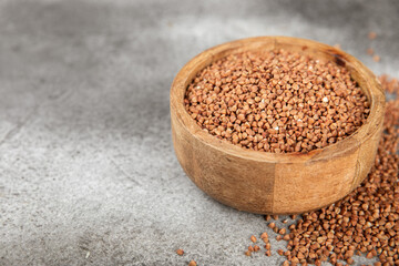 Raw buckwheat in a bowl on a textured background.Wheat grains, porridge, cereals, raw buckwheat in a plate. Healthy food. Porridge. Diet. Organic cerea. Space for text.Copy space.