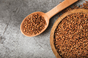 Raw buckwheat in a bowl on a textured background.Wheat grains, porridge, cereals, raw buckwheat in a plate. Healthy food. Porridge. Diet. Organic cerea. Space for text.Copy space.