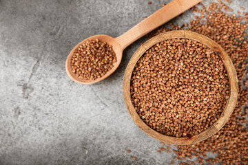 Raw buckwheat in a bowl on a textured background.Wheat grains, porridge, cereals, raw buckwheat in a plate. Healthy food. Porridge. Diet. Organic cerea. Space for text.Copy space.