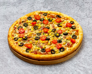 Homemade Italian style pizza with cheese, olives, corn, bacon, chicken and cherry tomato close-up on a wooden board on the table. Horizontal